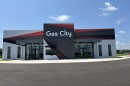 A building fronted with black, red, and gray graphics stands under a clear sky. The name reads Gas City Performing Arts Center.