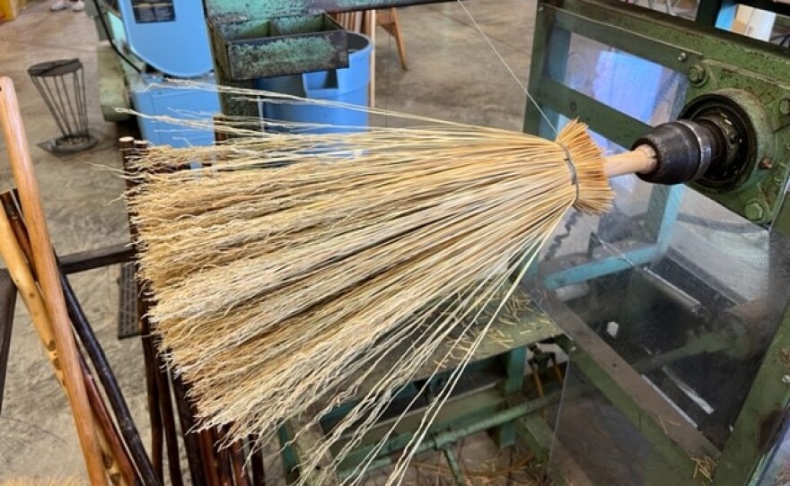 A machine helps attach the broomcorn to a stick