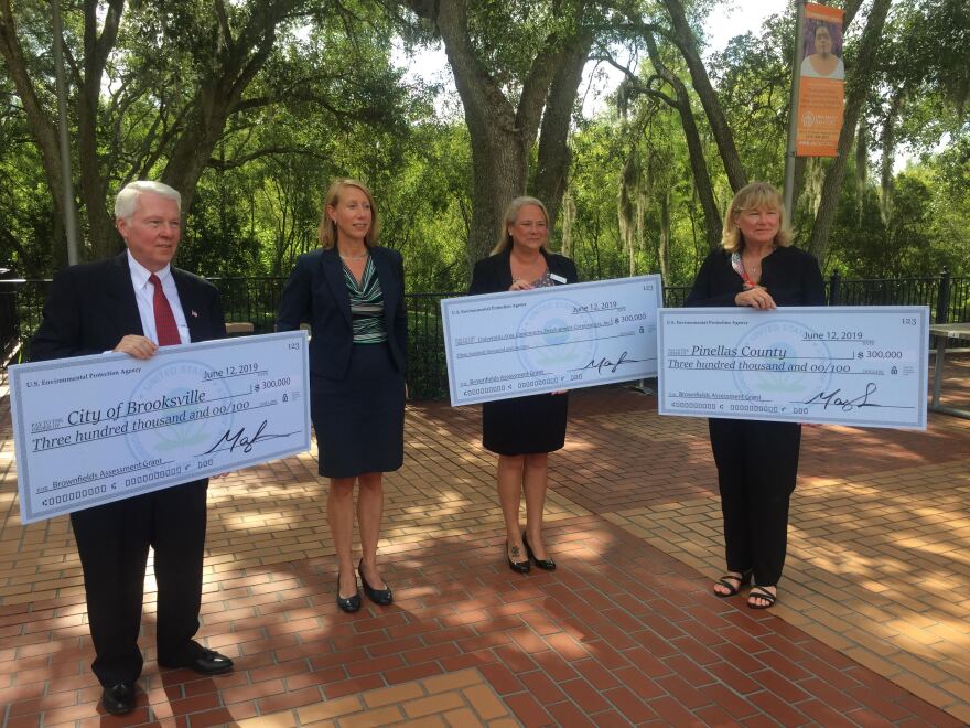 William Kemerer, Pat Gerard, and Josie Rocco accept checks on behalf of Brooksville, University Area in Tampa, and Pinellas County. 