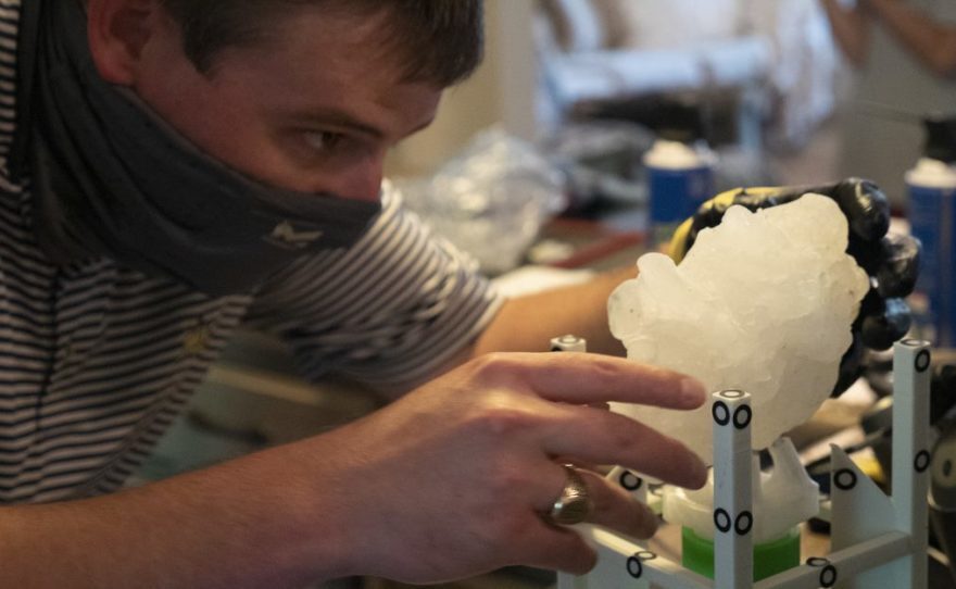 Giant Hailstone on a stand while male scientist examines it. 