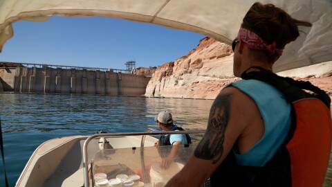 FILE - Utah State University master's student Barrett Friesen steers a boat near Glen Canyon dam on Lake Powell on June 7, 2022, in Page, Ariz.