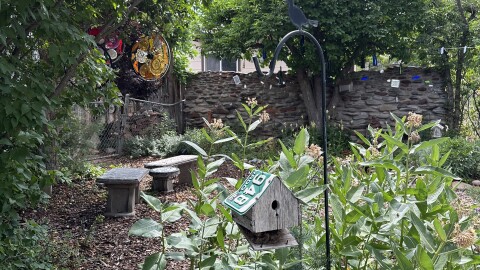 Front garden entrance with bird house, mosaic tiled benches, and bicycle glass wheels.