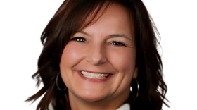 A smiling woman with shoulder-length brown hair wearing a white turtleneck sweater