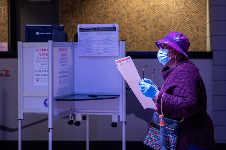 A woman stands in line with her ballot in order to have it scanned and counted on the first day of early voting at Capital One Arena in Washington, D.C., U.S., on Tuesday, October 27, 2020.