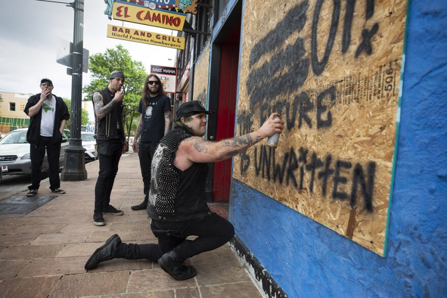 Zach Volta, chef at Casino El Camino, spray paints the boarded-up window on the front of the Sixth Street restaurant as his coworkers watch March 19