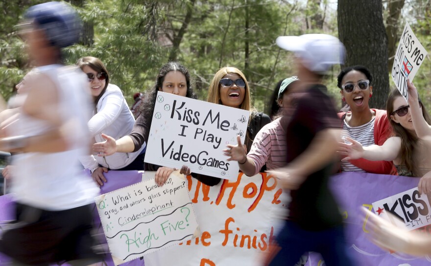 Wellesley College student Whitney Fahnbulleh (center right) holds a sign as runners pass the college during the race. About 36,000 athletes participated in the first running of the race since last year's bombing.