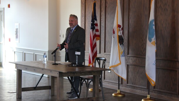 Congressman Eric Sorensen hosts a town hall in Peoria Ill. Stands in front of three flags. American Illinois and Peoria. 
