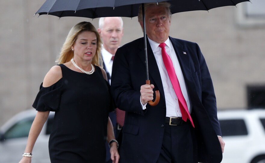 Republican nominee Donald Trump holds an umbrella while walking in the rain with Florida Attorney General Pam Bondi, as they arrive at a campaign rally in Tampa, Fla., in August.