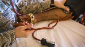 A New Jersey Air National Guard member checks the blood pressure of a homeless veteran