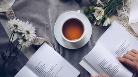 A tabletop with two open poetry books and a cup of coffee.