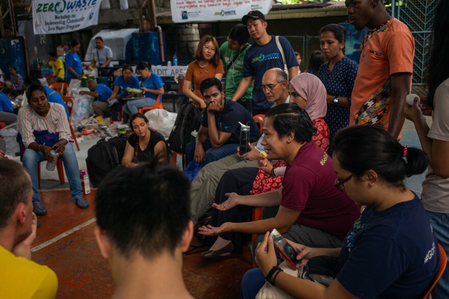 Froilan Grate publicizes the logos on plastic trash to encourage manufacturers to find alternatives. Above, he speaks to foreign visitors who face a similar dilemma.