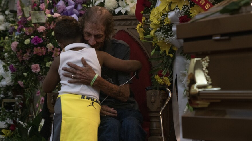 Antonio Basco hugs a boy at the memorial service for his wife, Margie Reckard, at La Paz Faith Memorial and Spiritual Center in El Paso, Texas. Basco, who doesn't have many local friends and family, invited the public to attend.