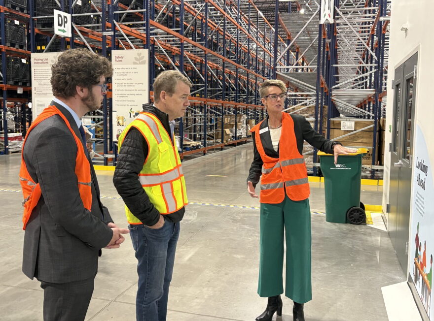 Erin Pulling, right, CEO of Food Bank of the Rockies, talks to U.S. Sen. Michael Bennet, middle, and Ron Meehan, government relations manager for Feeding Colorado in a large warehouse.