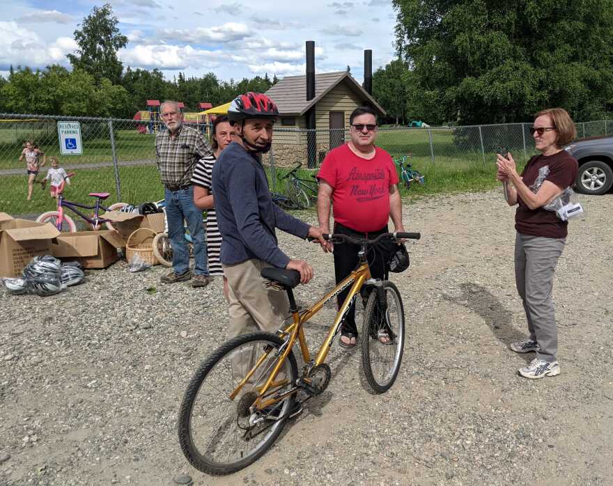 Sasha Cheriesiuk shows off his new bike and helmet as bystanders look on. From left, they are Potts; Kravets; Oleg Barladyan, Cheriesiuk's son-in-law; and Flory.