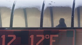 A thermometer shows the temperature as a man walks to a parking garage during the cold winter weather.