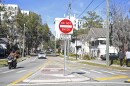 Pedestrians and a motorcyclist walk past one-way signage visible on Tuesday at the traffic circle at the intersection of Southwest Second Avenue and Southwest 12th Street in Gainesville.