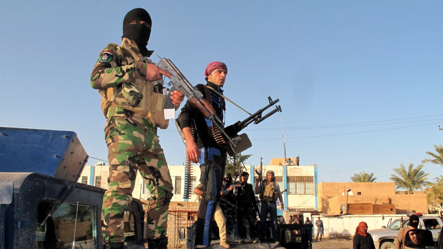Tribesmen and Iraqi police forces hold a position in a street of the city of Ramadi, west of the capital Baghdad, on Jan. 30, during a military operation against anti-government fighters.