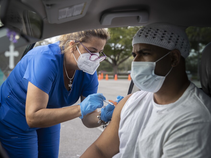 Alejandro Brown receives a COVID-19 vaccine from a health care worker at a drive-thru site in Miami on Dec. 16.