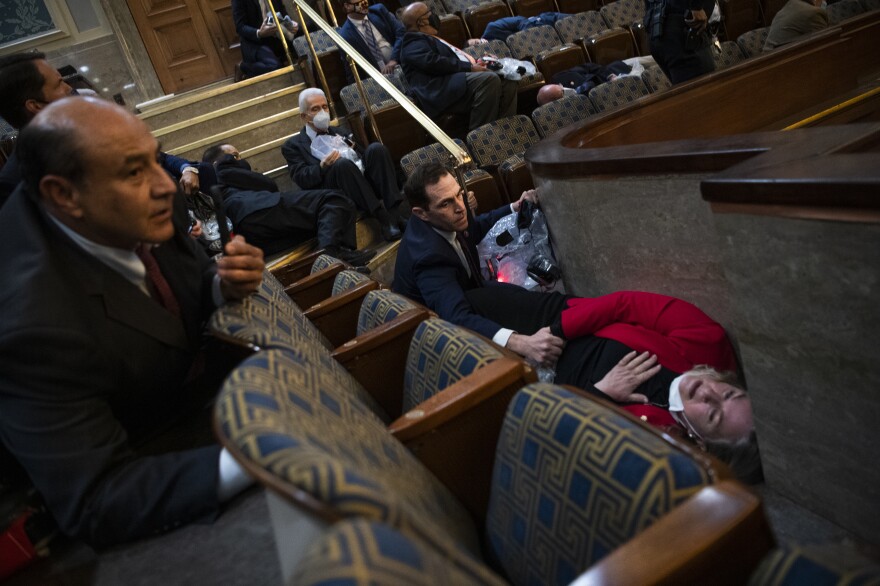 Rep. Jason Crow, D-Colo., comforts Rep. Susan Wild, D-Pa., while taking cover as rioters disrupt the joint session of Congress to certify the Electoral College vote.