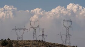 FILE - Power lines with smoke plumes in the background on July 12, 2021, near Klamath Falls, Ore. On Thursday, lawmakers passed House Bill 3792, which will double the funding for the Oregon Energy Assistance Program to help qualified low-income residents pay their electric bills and avoid having their power turned off.