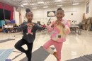 Two students practice a yoga pose in school.