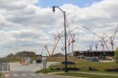 A construction vehicle enters Intel's One Ohio manufacturing site through a gate. Mounds of dirt rise on the horizon, and dozens of tall construction cranes tower over a partially built building. 