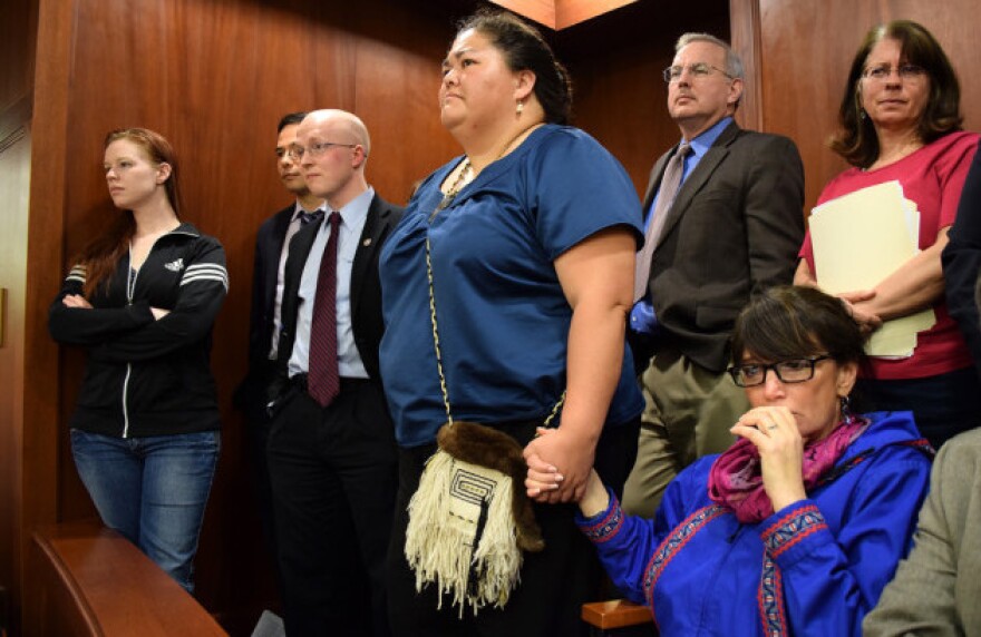 Just before Alaska's Senate voted to make 20 Alaska Native languages official state languages alongside English, Rep. Charisse Millett (seated) held hands with Liz Medicine Crow. Left of them is Rep. Jonathan Kreiss-Tomkins, who introduced the bill.