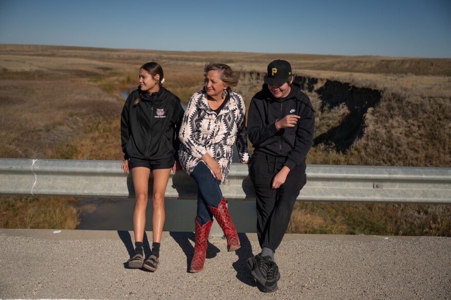 Tescha Hawley (center) sits for a portrait with her children, Tearia Sunchild (left) and Trayce Sunchild, near Jim Brown Creek on the Fort Belknap Indian Reservation in Montana. Tescha says hospital bills from her son’s birth that the Indian Health Service promised to pay were sent to debt collectors in her name. The financial consequences lasted years. (Jessica Plance for KFF Health News)