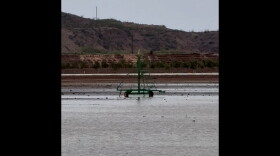 Photo of water coming over the top of the dam in the distance