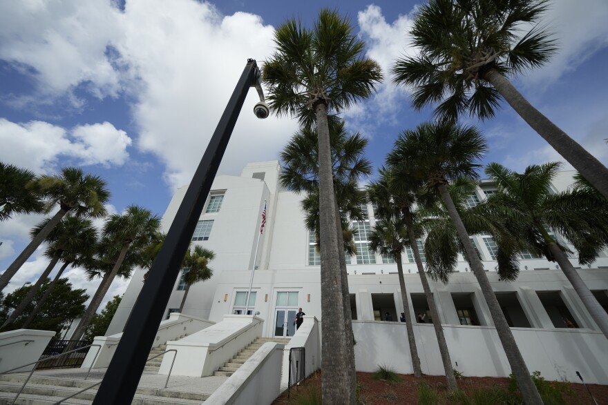 A large white building with palm trees outside. 