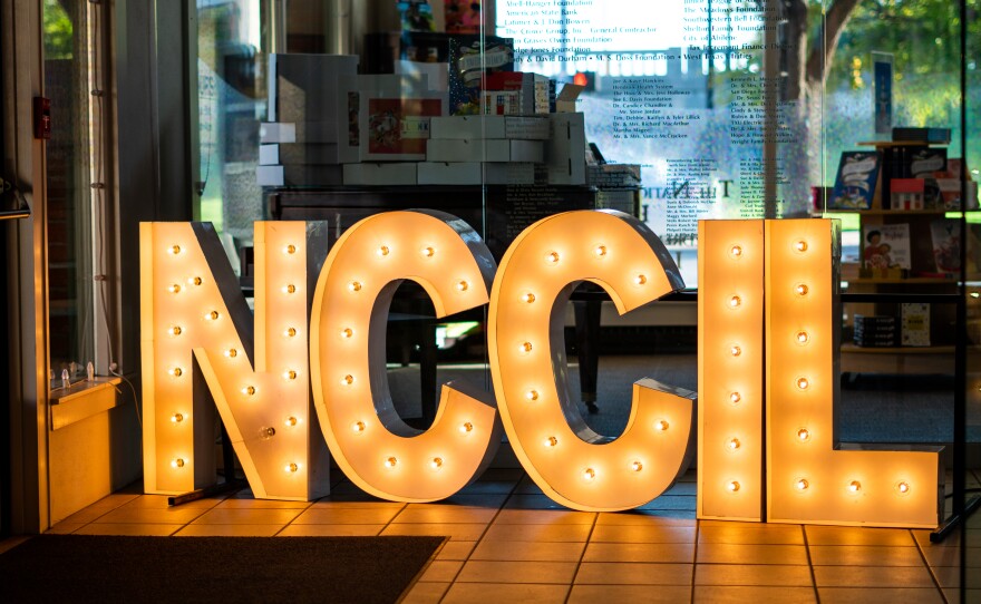 The National Center for Children's Illustrated Literature sign glows amongst the exhibition.