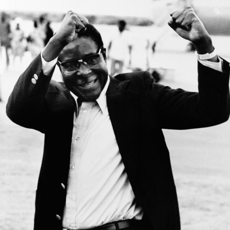 Robert Mugabe raises his fists in salute to a group of supporters as he arrives at Lusaka Airport, Zambia, to attend an African leaders' summit conference in January 1977.