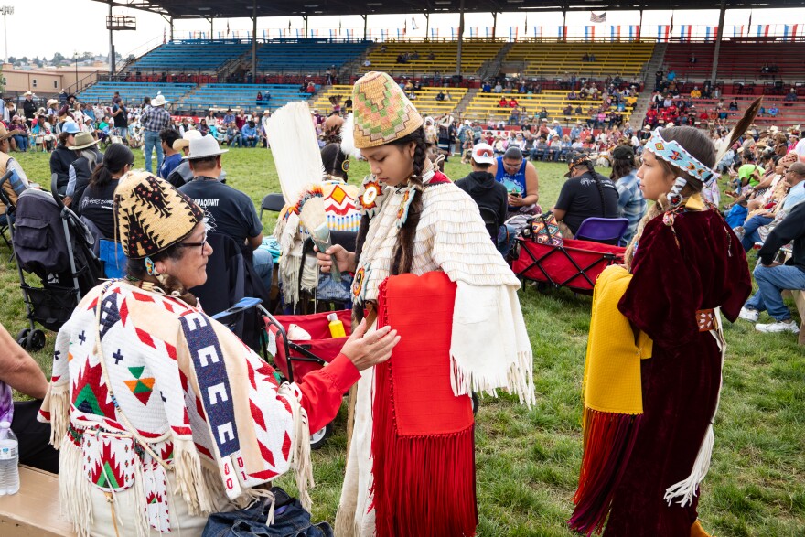 At the 2024 Pendleton Round-Up Traditional Ceremonial Dance, Pinkham helped her granddaughter, Nani Lynnette Meninick, get ready to dance in the Junior Girl’s Traditional category. Meninick danced in a dress made by Pinkham and with a red shawl, also by Pinkham. Meninick’s refurbished dentalium cape is a family heirloom.