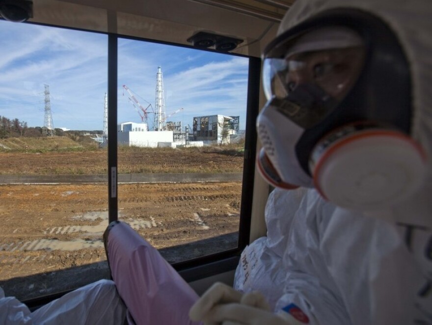 An official from the Tokyo Electric Power Co. (right), wearing a protective suit and mask, rides on a bus taking journalists by the crippled Fukushima nuclear power station in northeast Japan in November. Japanese officials say the plant is stable, but concerns about radioactivity remain a constant worry in many parts of Japan.