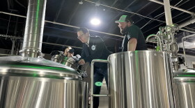 Gov. Josh Shapiro signs a Honesdale 'Main Street Matters' sign on top of brewing equipment at Runaway Train Brewery