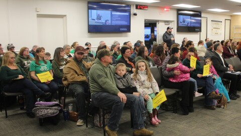 Audience members hold signs advocating to keep Kasilof's Tustumena Elementary School open during a school board meeting on Monday, Mar. 2, 2026 in Soldotna, Alaska.