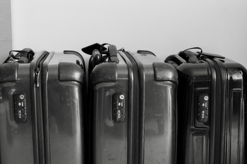 Three black suitcases sit in a row.