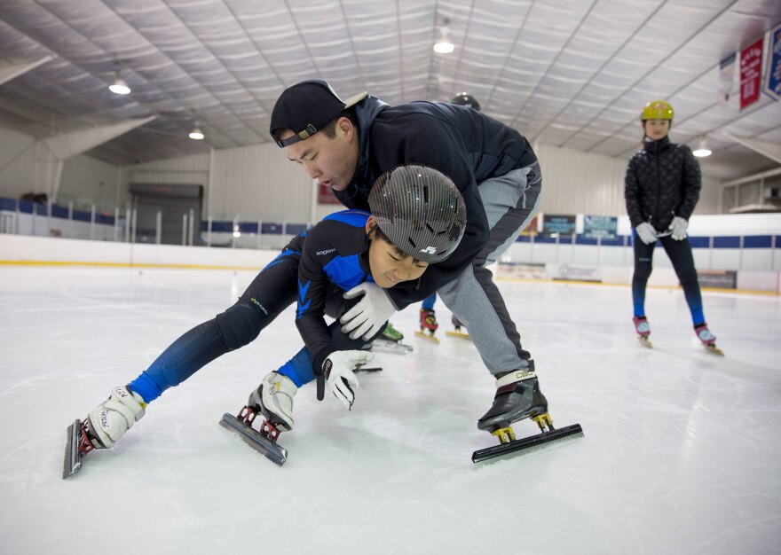 Soo An Yoo, a coach with Dominion Speedskating from South Korea, helps David Chun, 9, learn how to do tight turns as Kyubin Oh looks on.