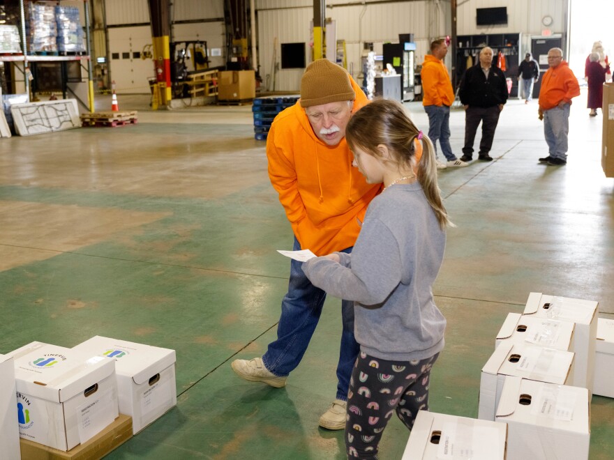 Mike Matejka helping a volunteer find a box of toys for a family at the Midwest Food Bank.