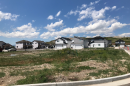 A row of houses leading into a cul-de-sac across a patchy field of grass.