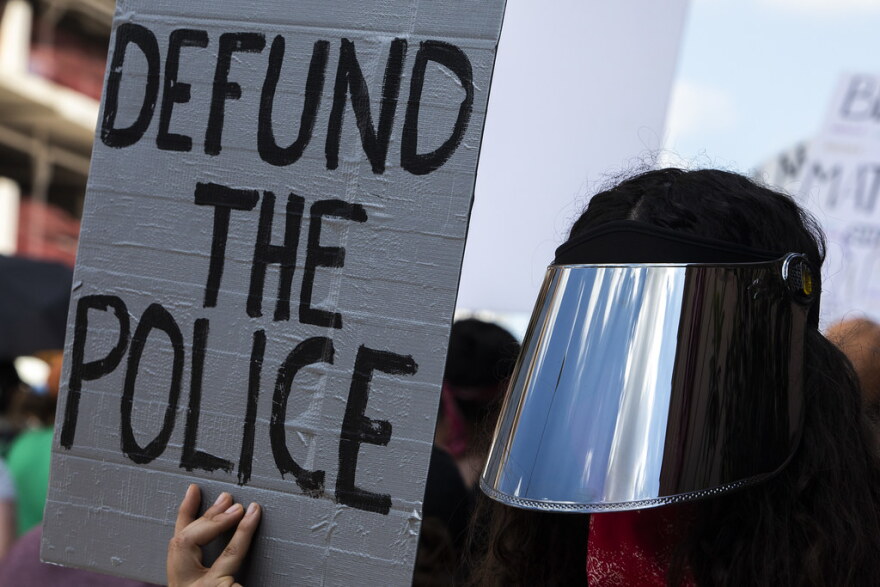 A protestor holds a sign calling for police defunding as thousands march from the Texas State Capitol to Huston-Tillotson University as part of the March for Black Lives. 