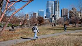 People walk on a sidewalk in front of large high rise buildings.