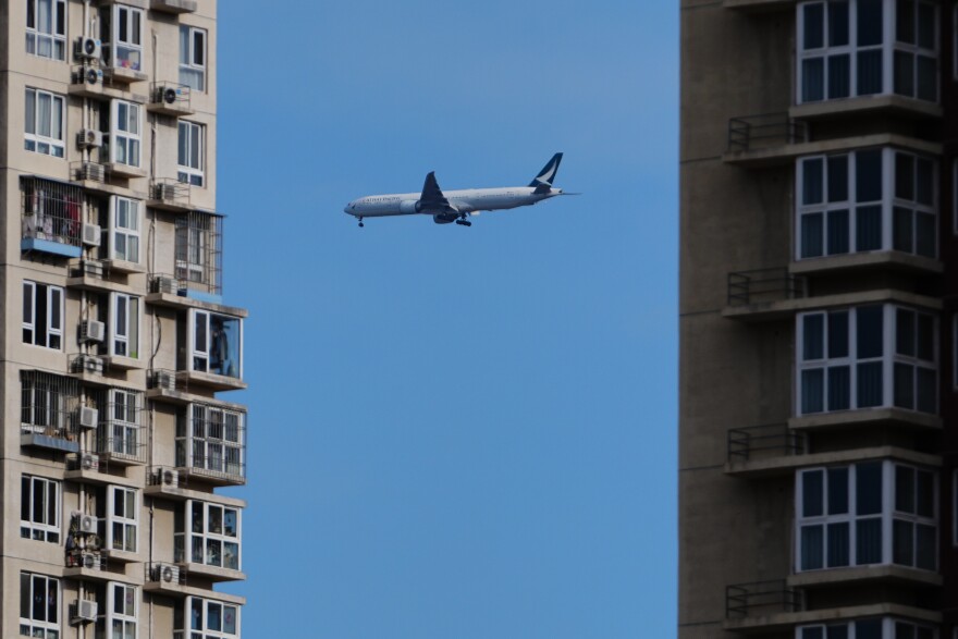 A Cathay Pacific airliner flies past residential buildings as it prepares to land at the Beijing Capital International Airport, in Beijing, Monday, Dec. 1, 2025. (AP Photo/Andy Wong)