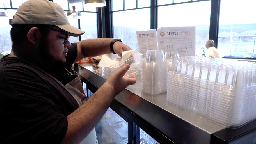 Karyawan Coffee Inclusive, Ayden Thomas, mengemas kue untuk pelanggan.