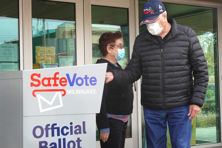 Residents drop mail-in ballots in an official ballot box outside of a Milwaukee library on Oct. 20, 2020.