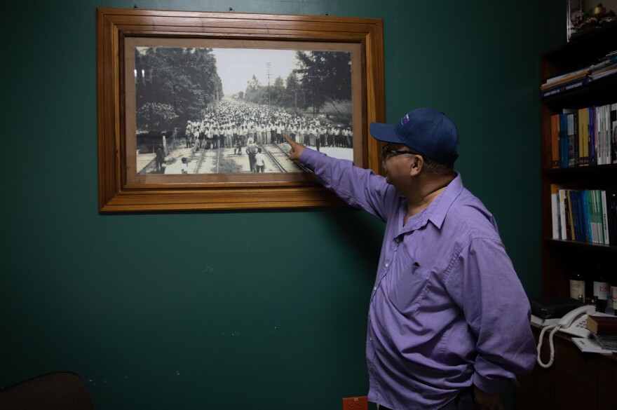 Father Ismael Moreno, better known as Padre Melo, a firebrand human rights advocate, points to a photograph in his office showing the labor movements that El Progreso has been known for.