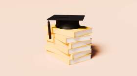 A clean, conceptual image featuring a neat stack of unmarked yellow books with a classic black graduation cap resting on top. The vibrant yellow tone conveys optimism, learning, and intellectual growth, while the academic cap represents success, accomplishment, and the culmination of education. The minimalist background enhances focus on the symbolic elements, making this image ideal for use in educational marketing, academic success themes, university admissions materials, or lifelong learning campaigns.