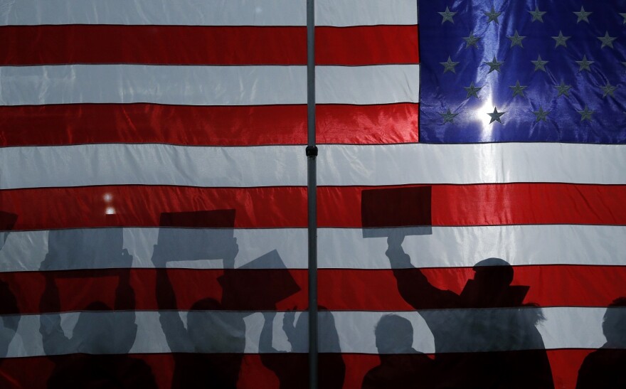 Silhouetted supporters wave signs at a campaign rally in Iowa ahead in January 2020.