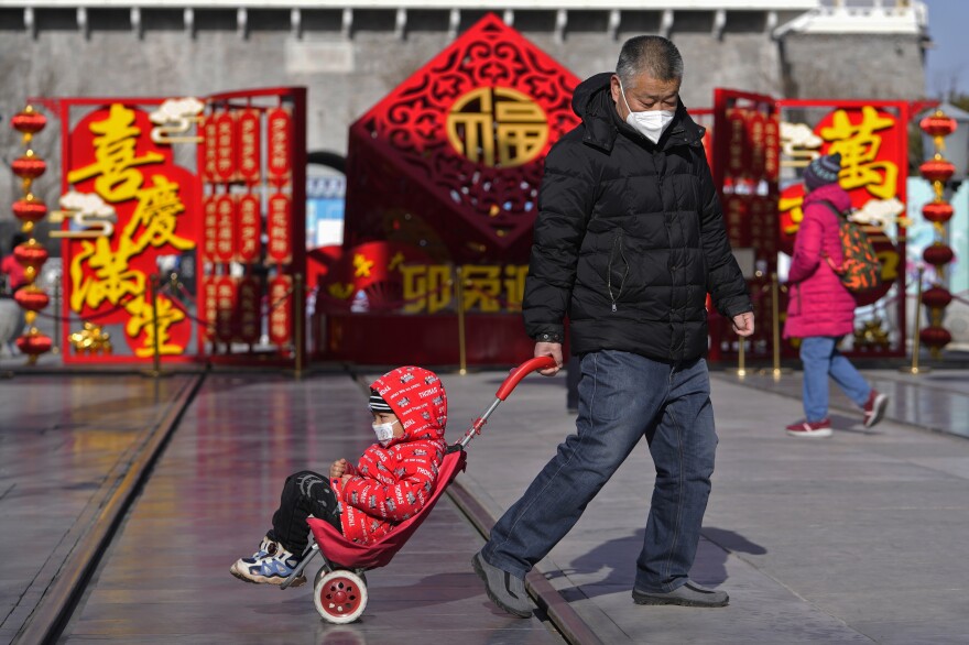 A man pulls a child past a Lunar New Year decoration on display at the Qianmen pedestrian shopping street, a popular tourist spot in Beijing, on Tuesday.