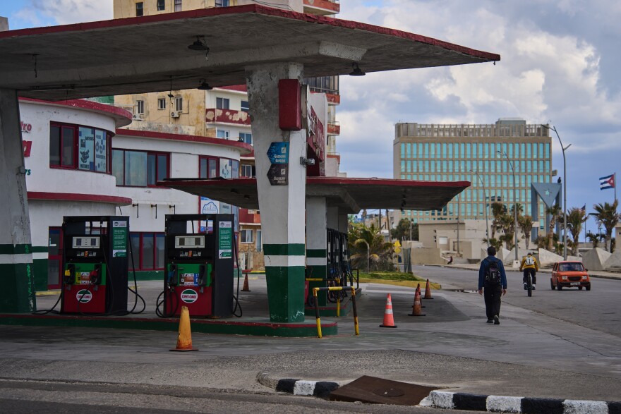 A man walks past a gas station that has run out of fuel, located near the U.S embassy, pictured in the background, in Havana, Cuba, Saturday, Feb. 7, 2026. (AP Photo/Ramon Espinosa)